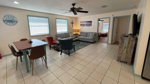 A spacious living area with a dining table, chairs, a sofa, and a ceiling fan. - JMJ BAY is Close to Beach in POC Charming Family Retreat (Port O'Connor)