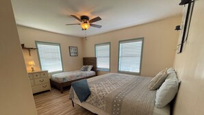 A bedroom with a large bed, two smaller beds, a dresser, and a ceiling fan. - JMJ BAY is Close to Beach in POC Charming Family Retreat (Port O'Connor)
