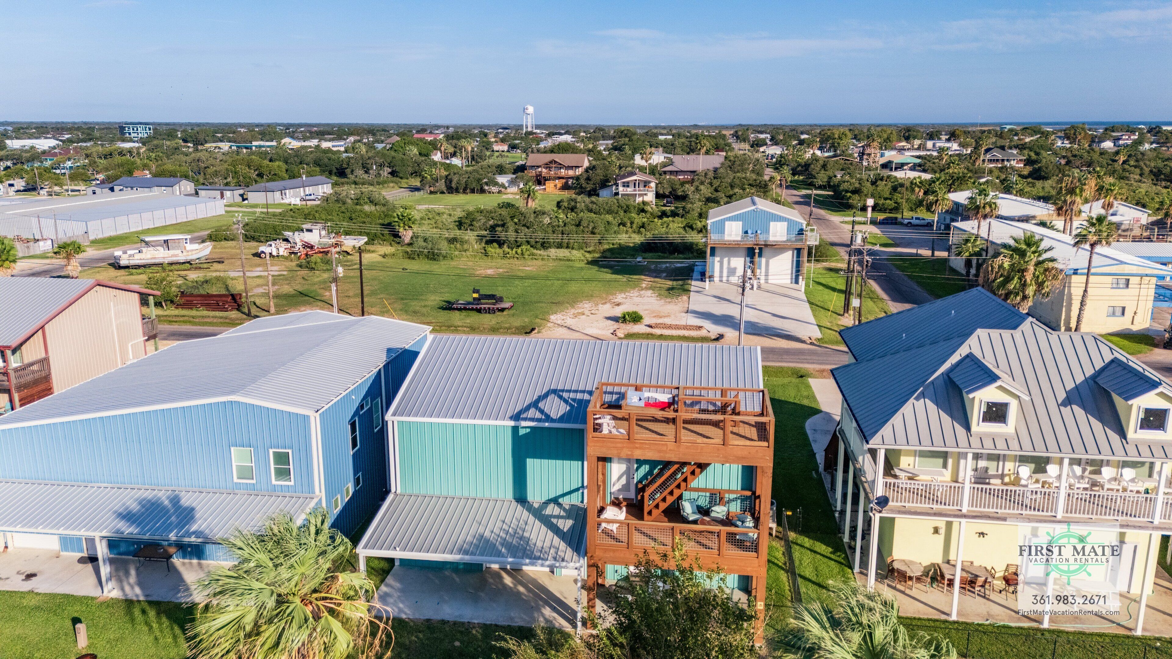 A residential area with multiple houses, including a prominent blue house with a wooden deck and a small tower-like structure.