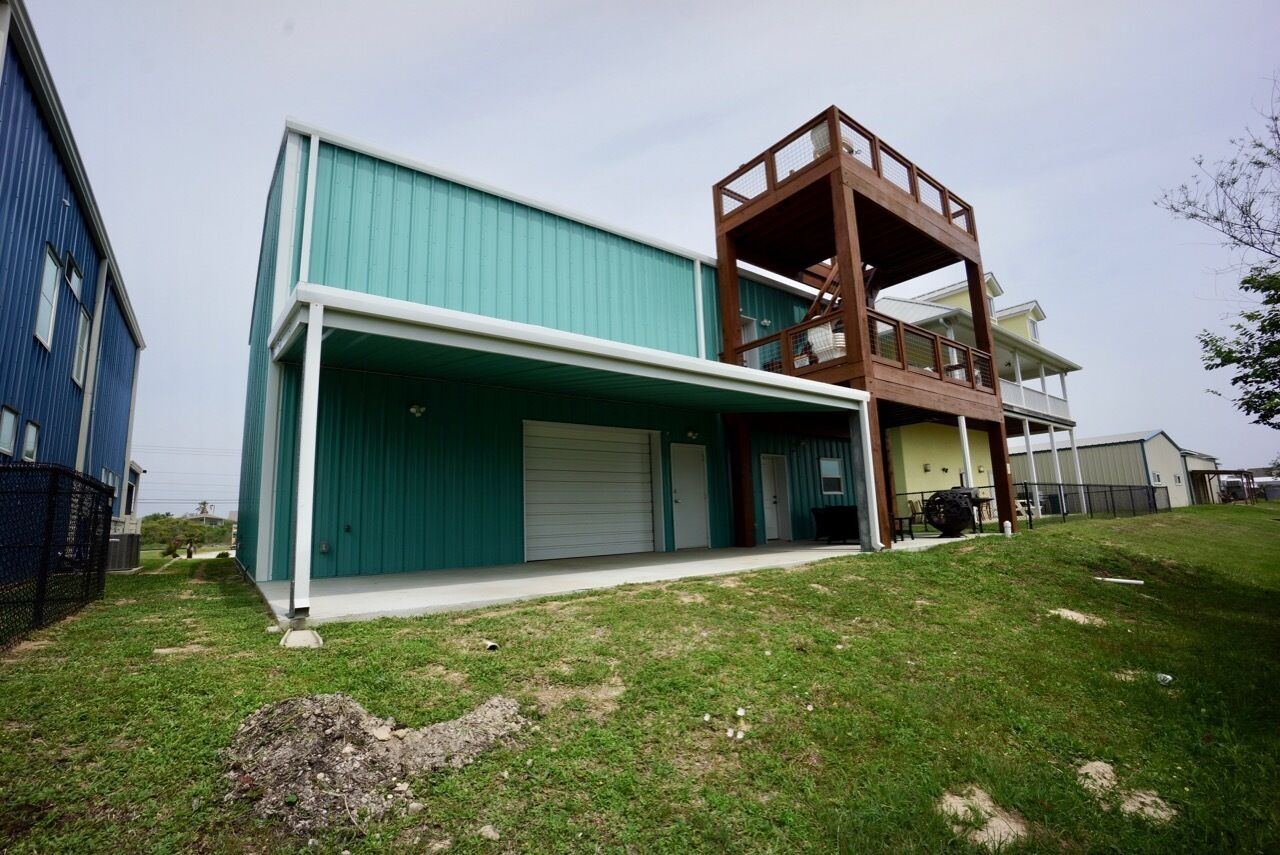 A modern two-story building with a flat roof and a large garage door.