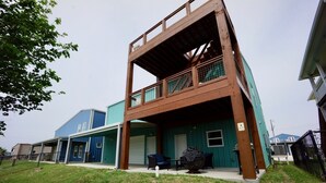 Een gebouw met twee verdiepingen, een overdekt terras, een blauwe gevel en een omheinde tuin.