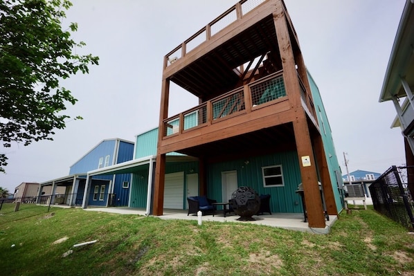 A two-story building with a covered patio area, a blue exterior, and a fenced yard.