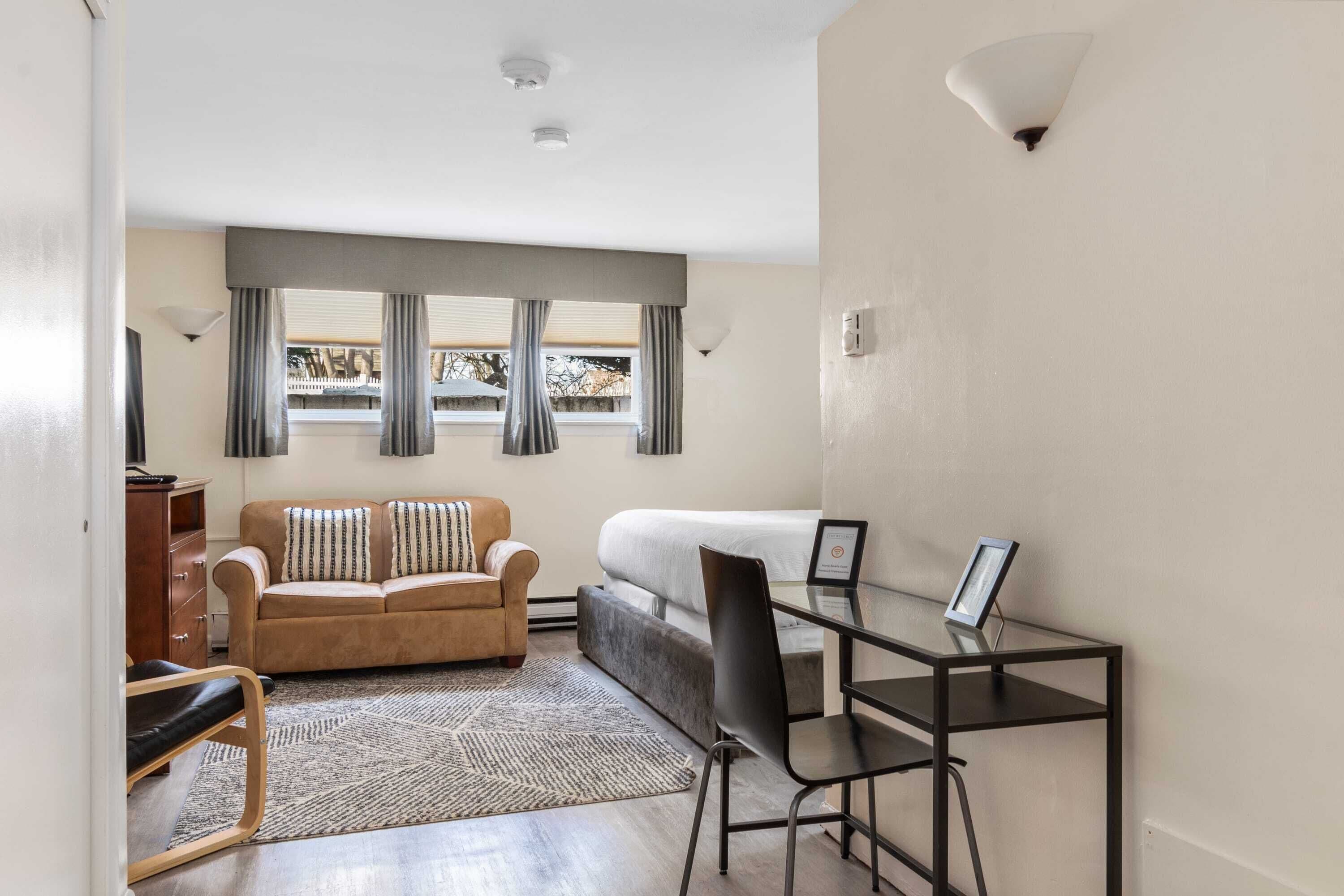 A compact room with a sofa, a desk, and a bed.