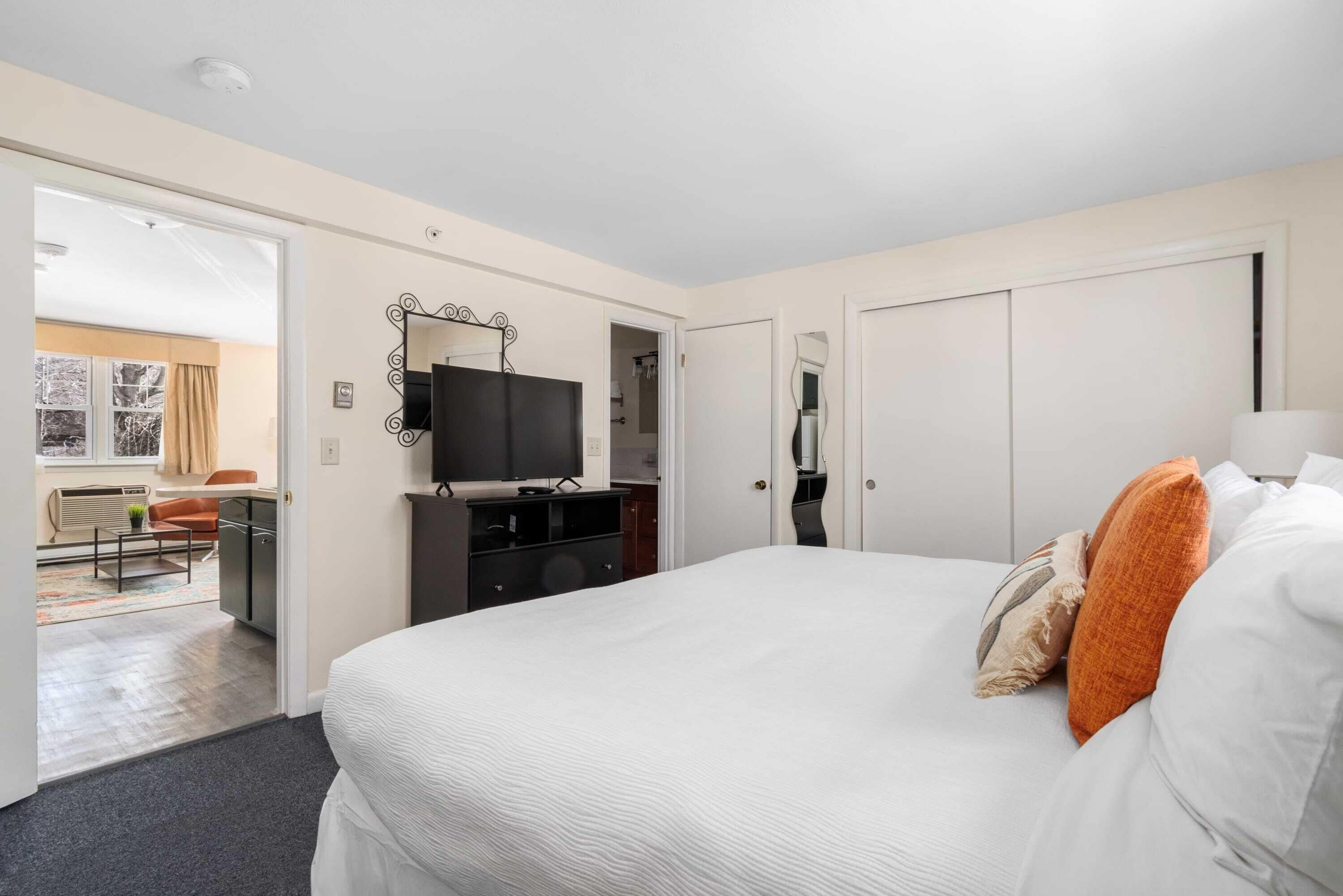A hotel room with a large bed, a TV, a desk, and a wardrobe.