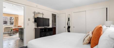 A hotel room with a large bed, a TV, a desk, and a wardrobe.