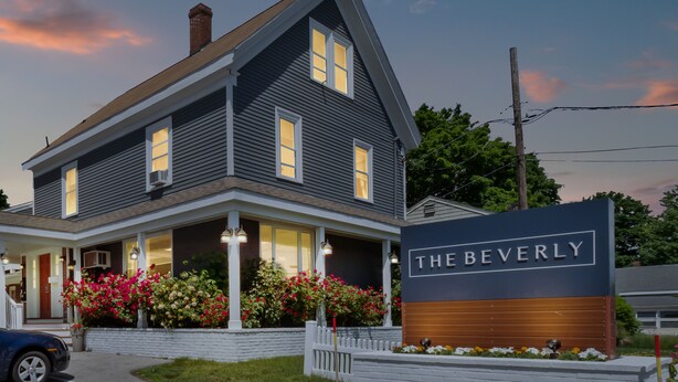 A two-story house with a porch, a sign reading "THE BEVERLY," and a brick foundation.