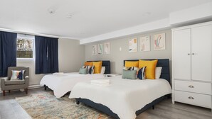 A hotel room with two beds, a wardrobe, a chair, and a window with curtains.