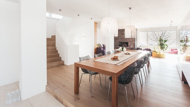 Un comedor moderno con una mesa de madera, sillas de estructura de alambre negro e iluminación colgante.