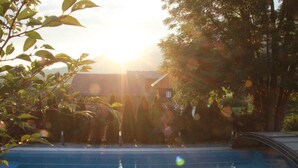 Una piscina con una vista despejada de los árboles circundantes y una casa al fondo.