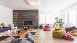 Una sala de estar moderna con chimenea de piedra, piso de madera y sillones orejeros coloridos.