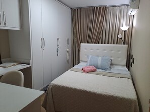 Un dormitorio con cama, escritorio y armario.