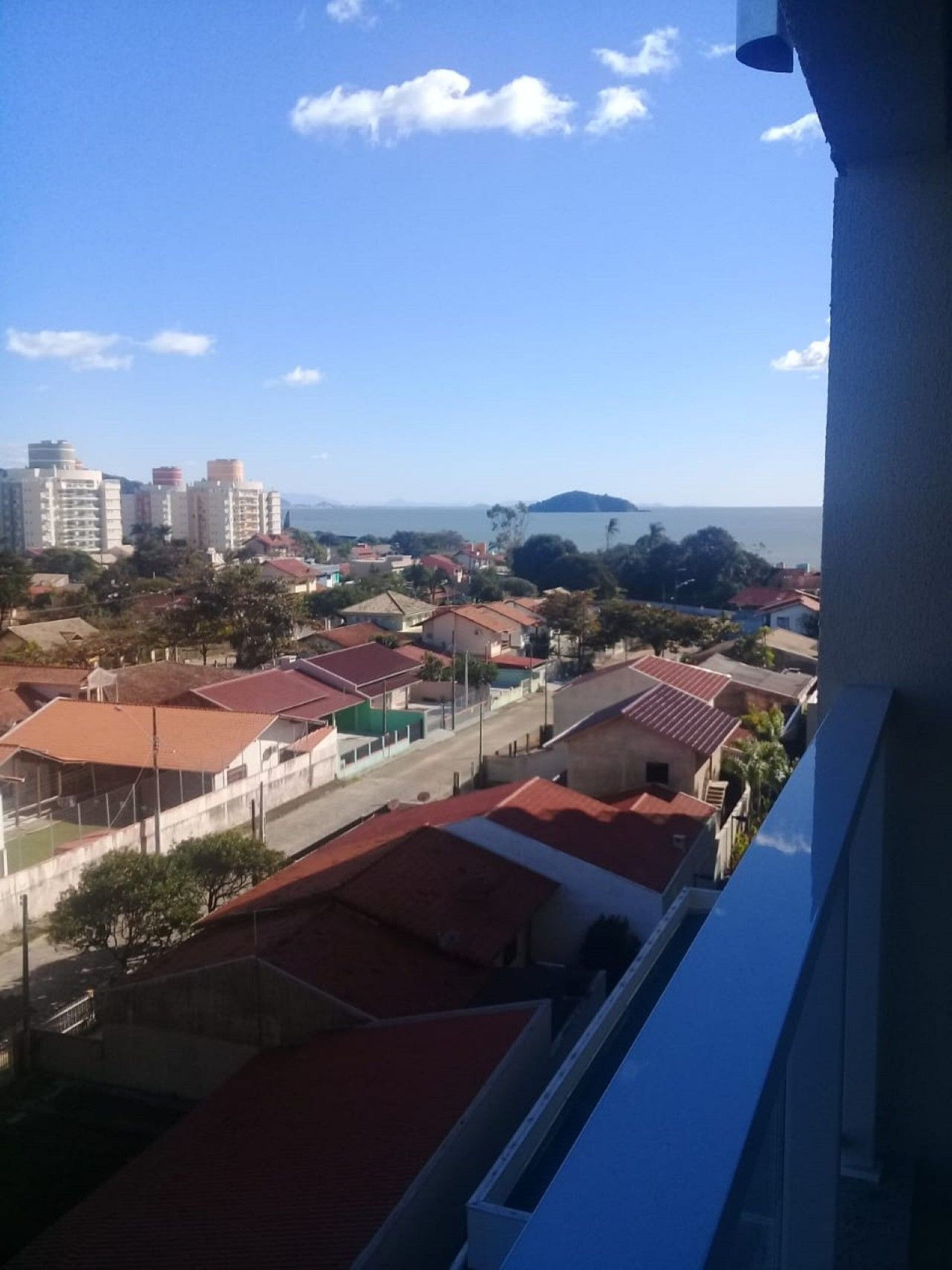 A view of a residential area with red-roofed houses and a distant body of water.