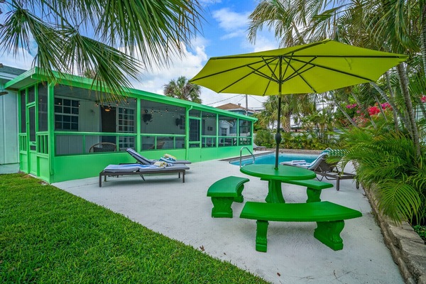 Large Backyard Pool with Lounge Chairs and Table Seating under the Palm Trees