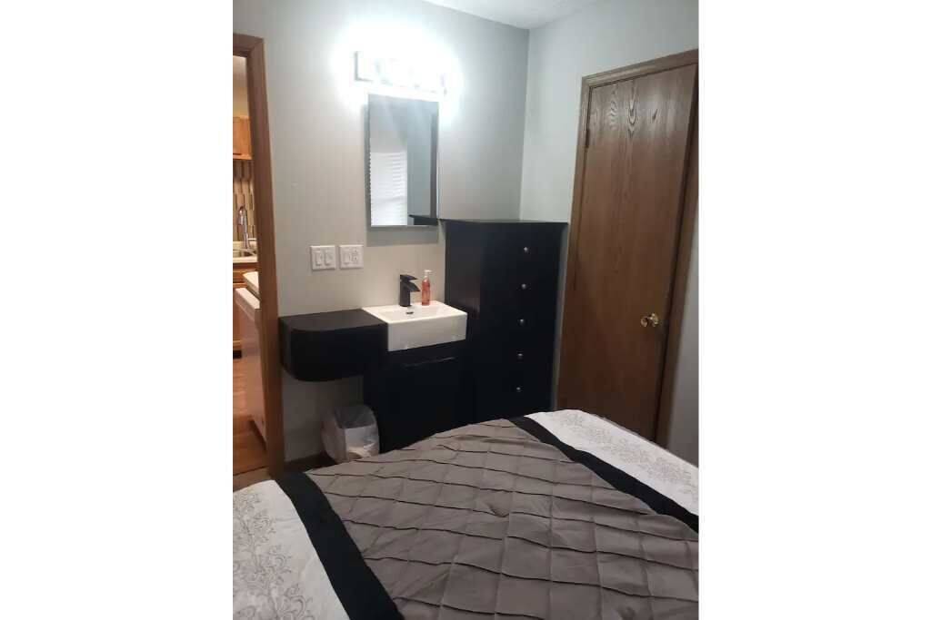 A bedroom with a bed, a bedside table, a mirror, and a wardrobe.