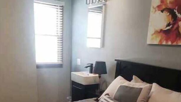 Ein Schlafzimmer mit Bett, Nachttisch, Lampe, Fenster und einem Bild an der Wand.