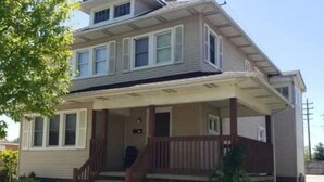 A two-story house with a front porch, a brick foundation, and a small front yard.