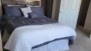 A bedroom with a bed, a wardrobe, and a door.