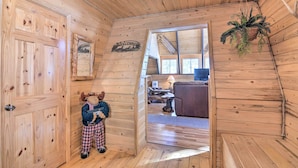 Un intérieur en bois avec une porte en bois, un jouet en peluche et une pancarte « Bienvenue ».
