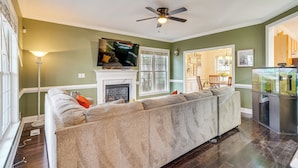 A living room with a large sectional sofa, a fireplace, a television, and a fish tank. - Wendell Home w/ Fenced Yard, Close to Raleigh (Wendell)