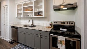 A kitchen with white cabinetry, a granite countertop, a stainless steel stove, and a dishwasher. - Enjoy the Fall & Winter Months in This Charming Home in Beautiful Marietta  (Marietta)