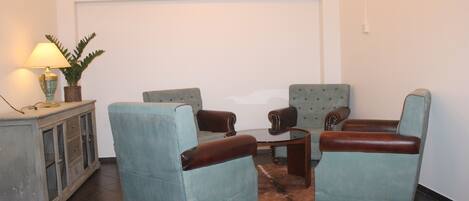 A living room with a sofa, two armchairs, a coffee table, and a cabinet.