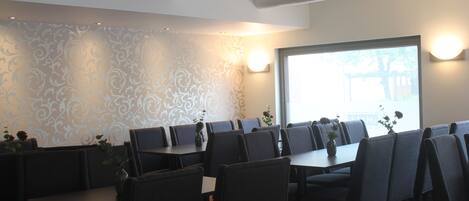A restaurant with booths and tables, patterned wallpaper, and wall-mounted lights.