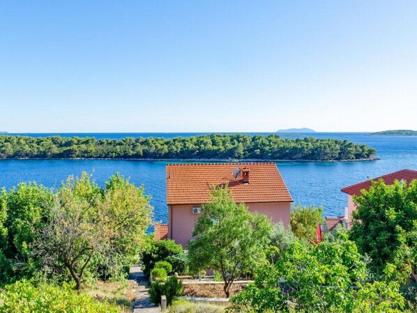 A coastal property with a view of the sea and a small island in the distance.