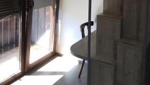 Una escalera que conduce a un segundo piso, una puerta con panel de vidrio y una pequeña mesa con sillas.