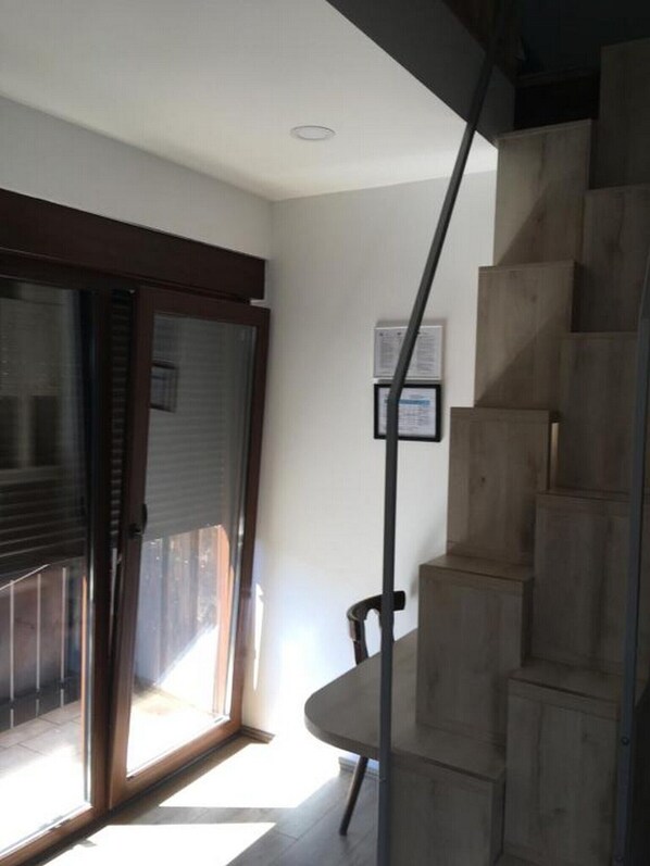 Una escalera que conduce a un segundo piso, una puerta con panel de vidrio y una pequeña mesa con sillas.