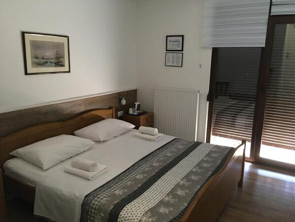 Ein ordentlich bezogenes Bett mit einem Holz-Kopfteil, ein Nachttisch mit Lampe und ein gerahmtes Bild an der Wand.