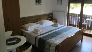 Une chambre à coucher avec un lit, une petite table, une chaise, une fenêtre et une porte.