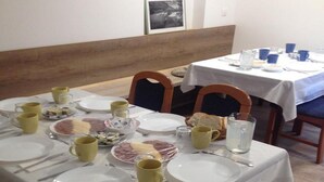 Un espace repas avec des tables mises pour le service, comprenant des assiettes, des couverts et des tasses.