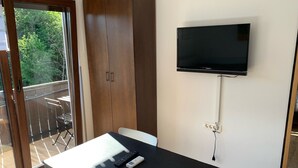 Une pièce avec une grande armoire, une table avec une télécommande et un téléviseur fixé au mur.