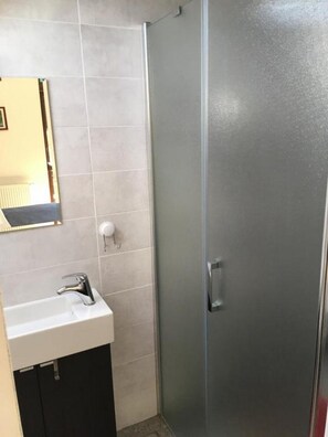 A bathroom with a white sink, a mirror, and a glass shower enclosure.