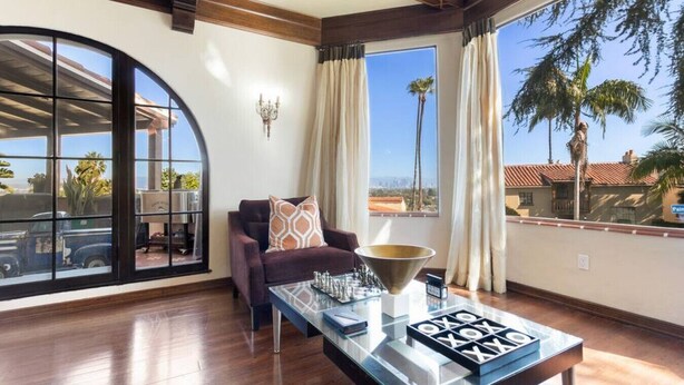 A spacious room with a large window, a comfortable armchair, a glass coffee table, and a decorative bowl.