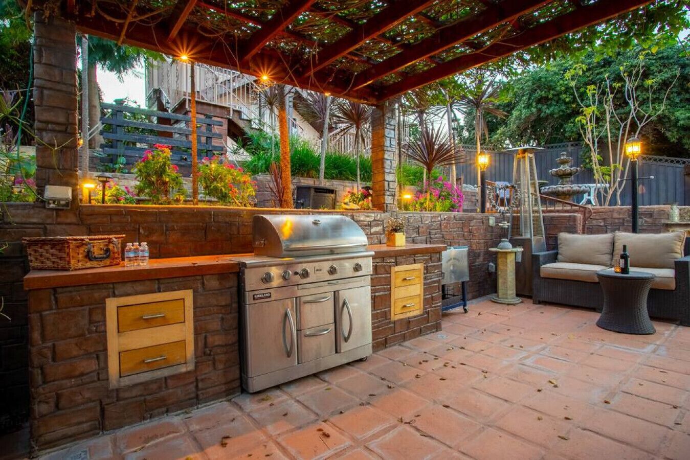 An outdoor kitchen with a grill, built-in drawers, and a stone counter.