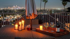 A terrace with a city view, candles, wine glasses, and a bottle of wine.
