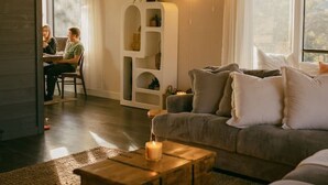 A living room with a sofa, a wooden coffee table, a ceiling fan, and a white shelving unit. - Pool Sunset View Game Room Full Kitchen (Redding)