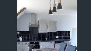 Une cuisine moderne avec des meubles blancs, un plan de travail noir et une table à manger avec des chaises.