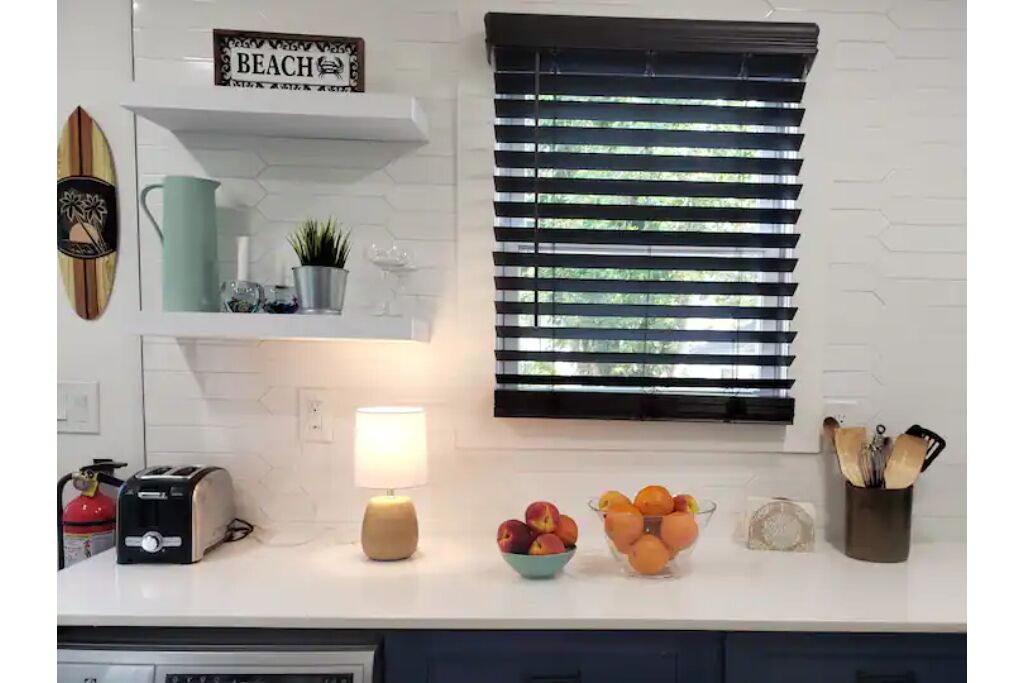 A kitchen with a toaster, a lamp, a bowl of fruit, and a sign that reads "BEACH".