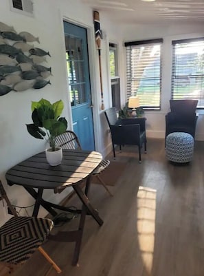 A dining area with a round table and chairs, a potted plant, and a wall art of fish.