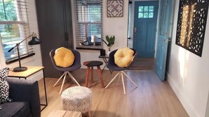 Un soggiorno moderno con un divano, due poltrone con cuscini gialli, un tavolino e pavimento in legno.