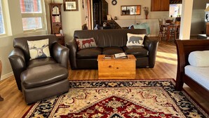 A living room with leather sofas, a coffee table, and a patterned rug. - Private, Cozy, and Remote Mountain Apartment in Walk-Out Garden Level w/Patio. (Black Hawk)