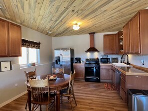 A kitchen with wooden cabinets, a stainless steel refrigerator, a stove, and a microwave.