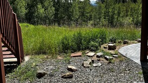 A covered outdoor area with a gravel path, wooden deck, and a view of a forested landscape. - Private, Cozy, and Remote Mountain Apartment in Walk-Out Garden Level w/Patio. (Black Hawk)