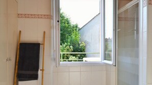 Ein Badezimmer mit Fenster, Handtuchhalter und Duschbereich.