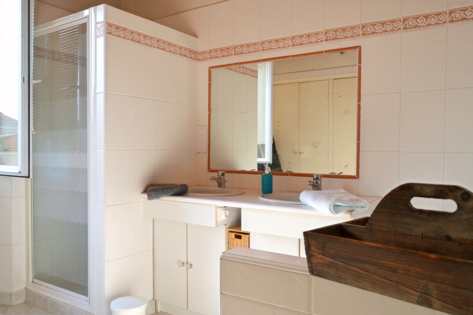 Ein Badezimmer mit Dusche, Waschbecken mit Spiegel und Holzwaschtisch.