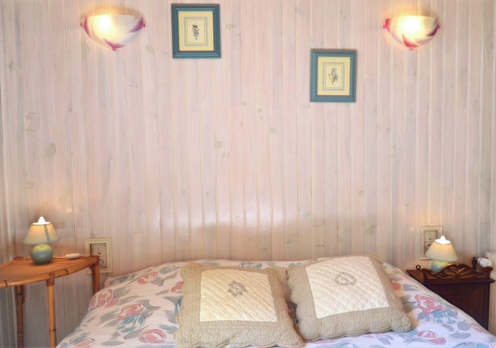 Un dormitorio con una cama, dos mesitas de noche y dos lámparas de pared.