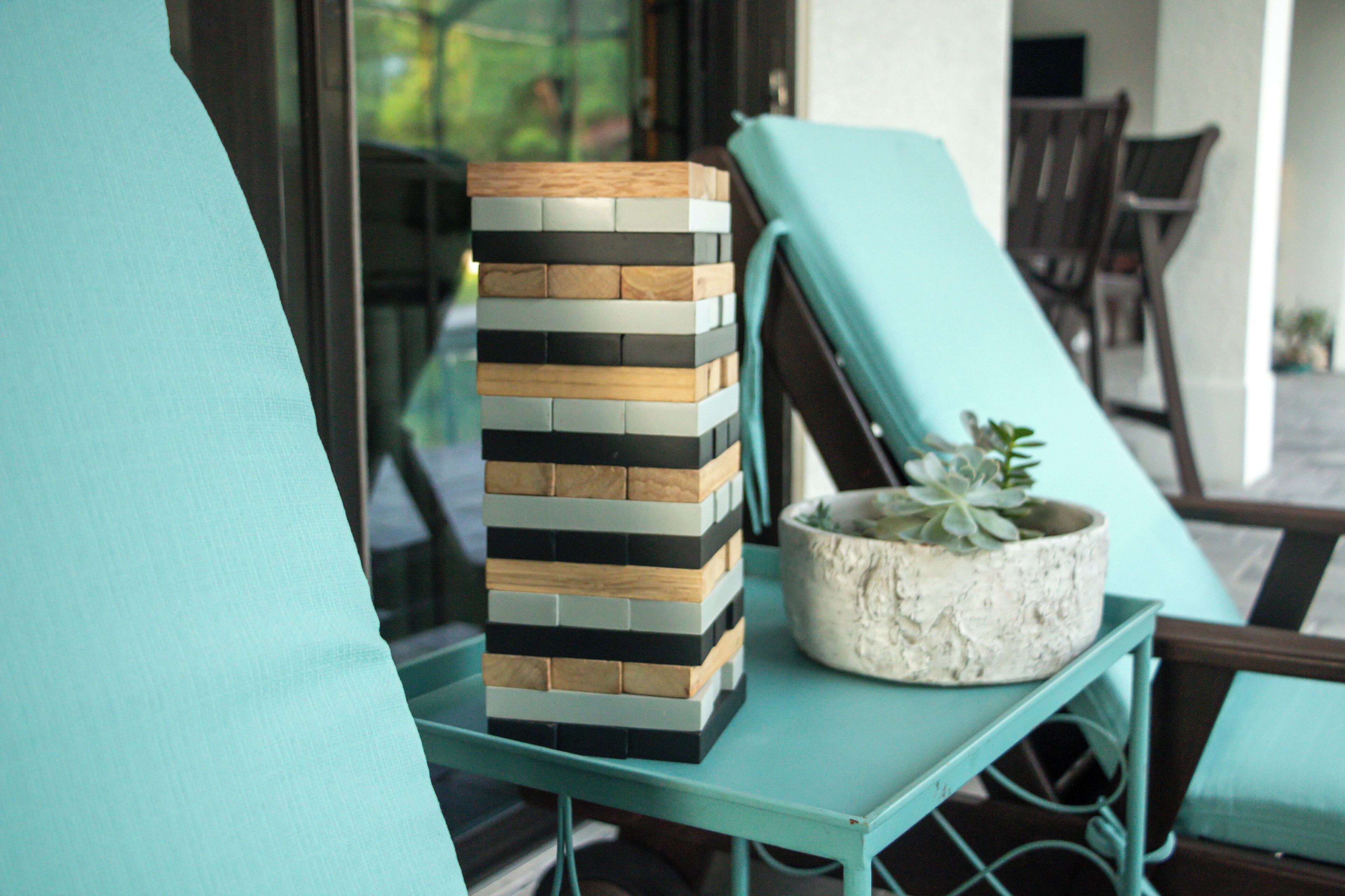 A stack of wooden blocks on a teal table, a potted plant, and a teal chair.