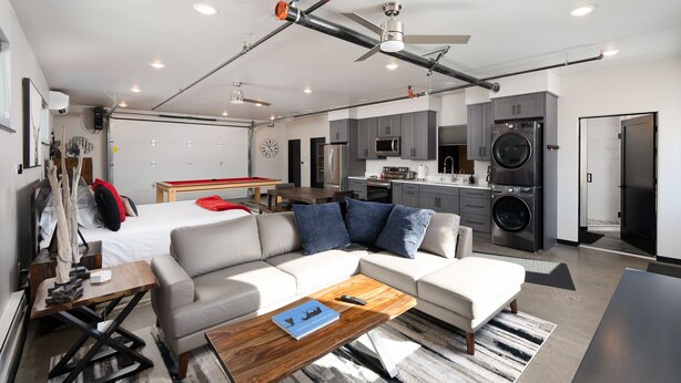 A modern, compact living space with a kitchenette, a dining area, and a bedroom. - Industrial Retreat Where Recreation Abounds! Dogs OK, Pool Table, BBQ & More! (Bozeman)
